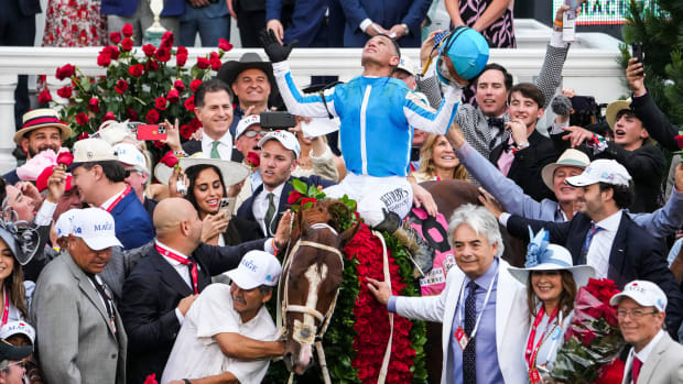 Jockey Javier Castellano celebrates aboard Mage in the Winner's Circle as trainer Gustavo Delgado Sr. puts a hand on the garland of roses after the 149th Kentucky Derby